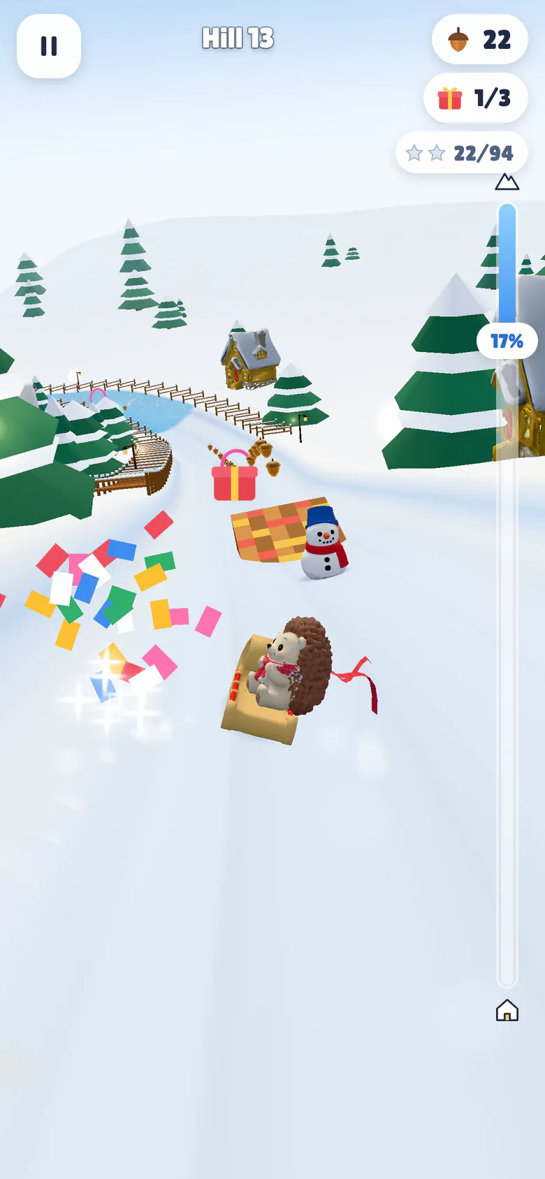 Hill 13 in Village Lanes: the hedgehog on its toboggan looks back over its shoulder as a present bursts into confetti beside a checkered ramp and a snowman, with a second present and a ring ahead and a cottage and an icy pond on the hillside.