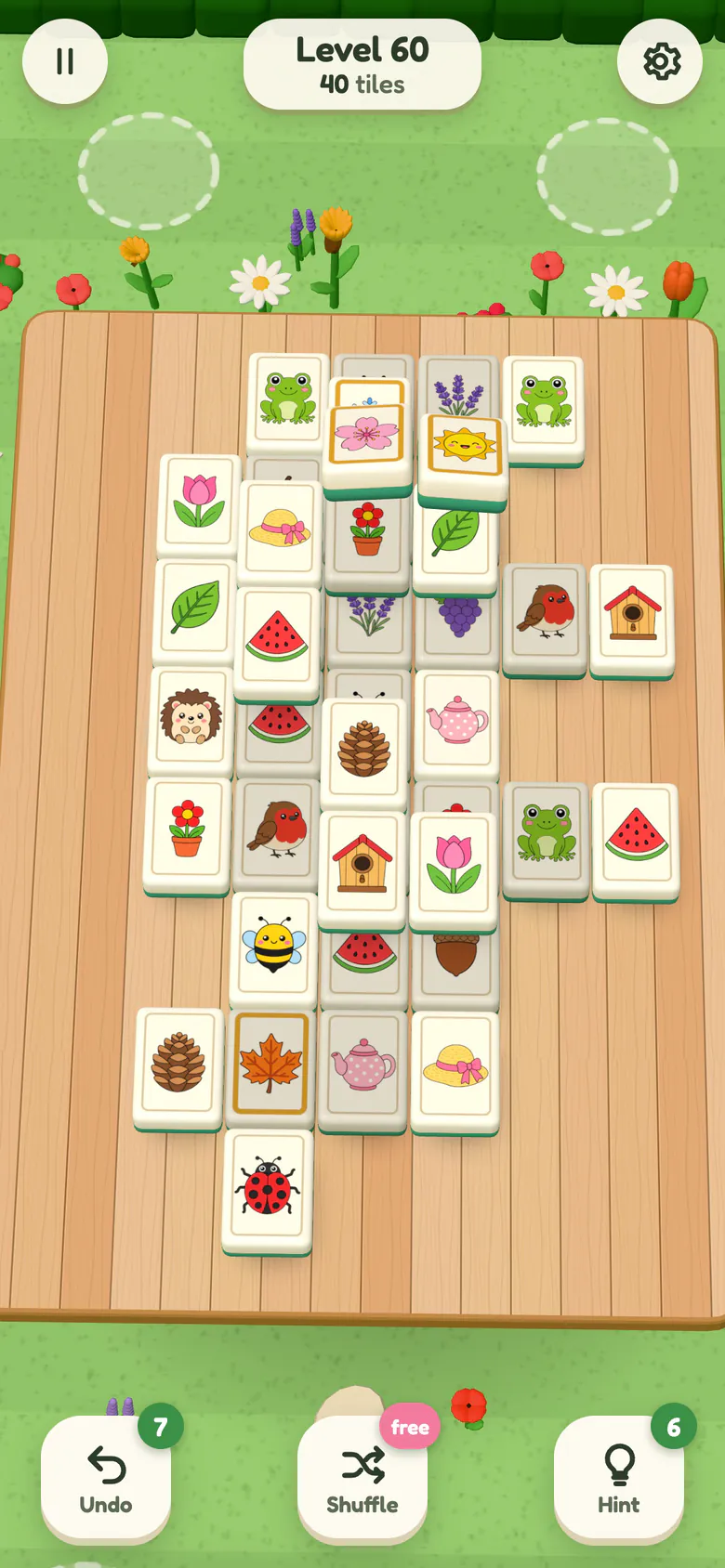 Level 60: two golden-framed season tiles, a pink blossom and a smiling sun, lift off the board together to be matched.