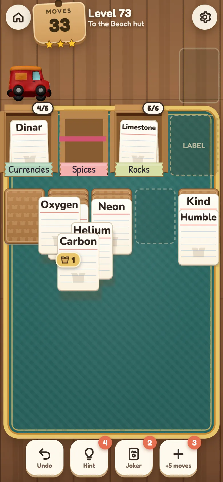 Level 73: three Elements cards, Oxygen, Helium and Carbon, slide together onto Neon in another column while the full Spices crate folds shut under its tape, next to the open Currencies and Rocks crates.